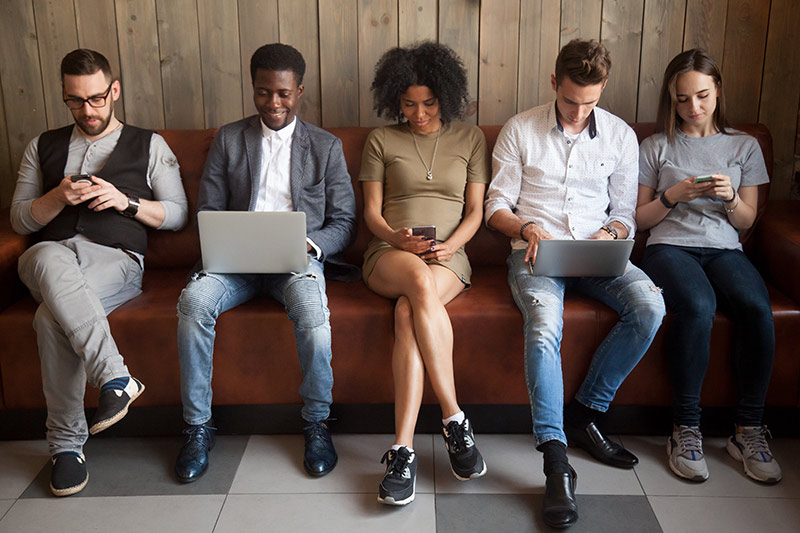 multicultural young people using laptops smartphones